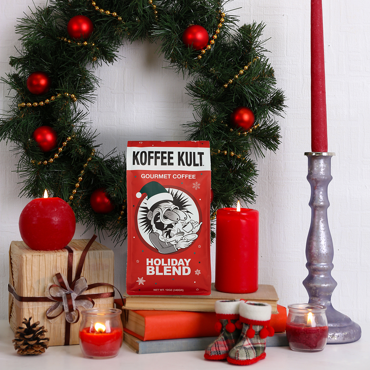 Koffee Kult holiday blend coffee package with Christmas decorations including a wreath, candles, and gift boxes.