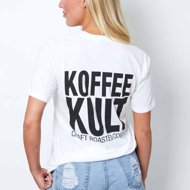 Person wearing a white t-shirt with 'KOFFEE KULT' text on the back, standing against a plain background.