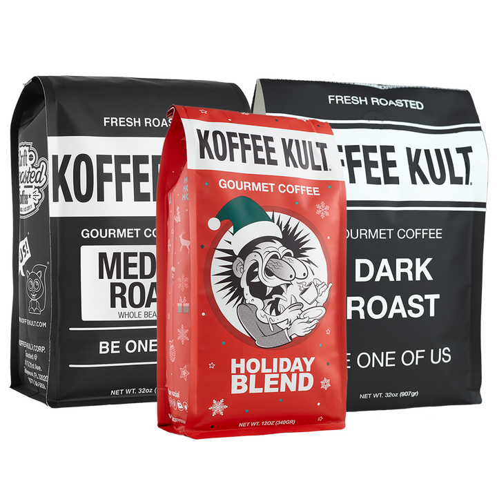 Three bags of gourmet coffee from Koffee Kult are displayed against a white background. In the foreground is a red bag labeled 'Holiday Blend', flanked by two larger black bags labeled 'Fresh Roasted' and 'Medium Roast' and 'Dark Roast' respectively.